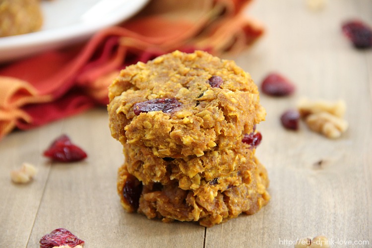 Pumpkin Breakfast Cookies stacked on a wooden board with dried cranberries