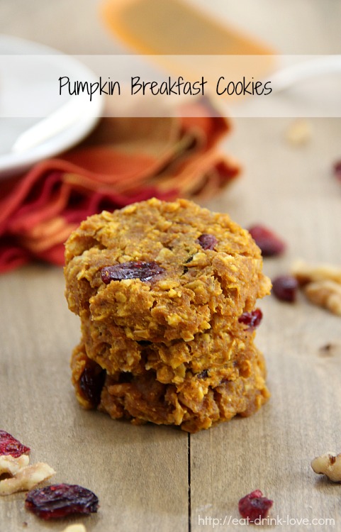 Pumpkin Breakfast Cookies stacked on a wooden board with dried cranberries