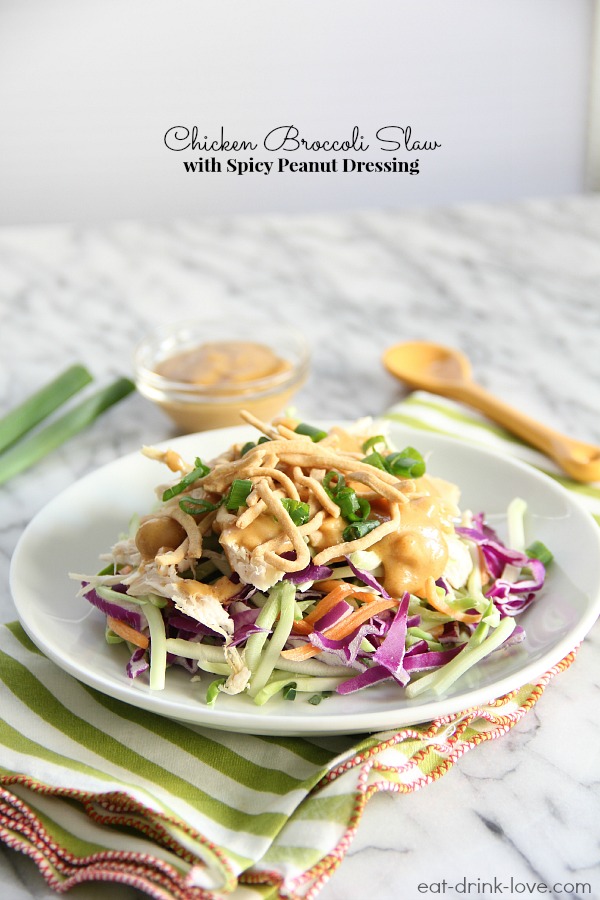Chicken Broccoli Slaw on a plate with peanut dressing on white marble board with a striped napkin