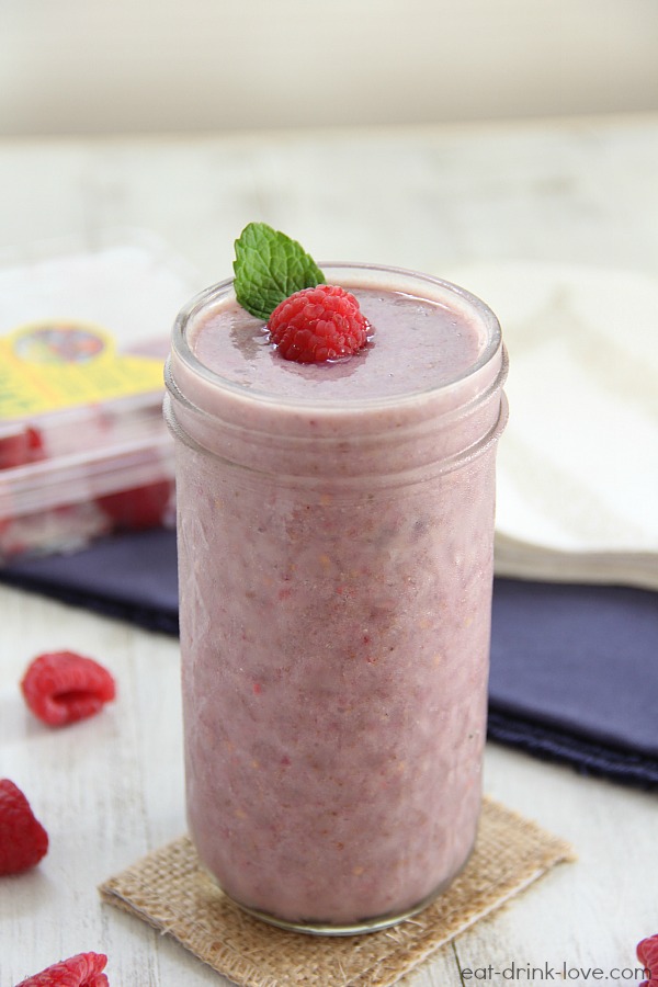 Raspberry Almond Smoothie in a glass jar with fresh raspberries on a white board