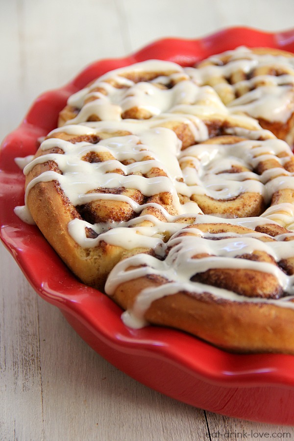 1-Hour Cinnamon Rolls with cream cheese drizzle in a red pie dish