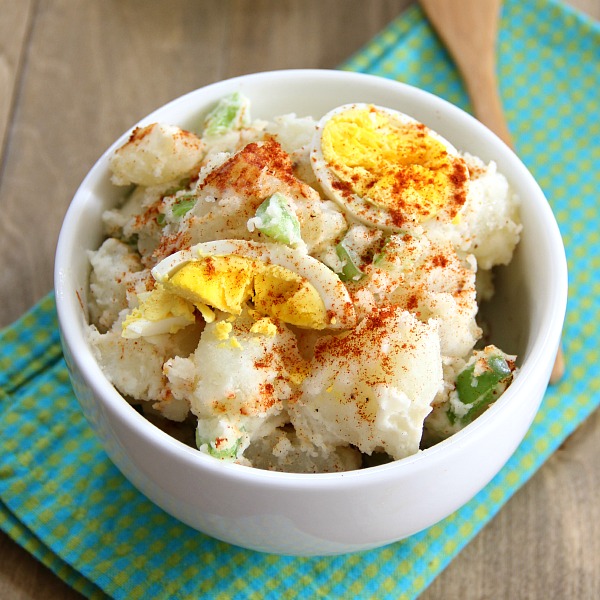 Dad's Potato Salad in a white bowl with paprika sprinkled on top