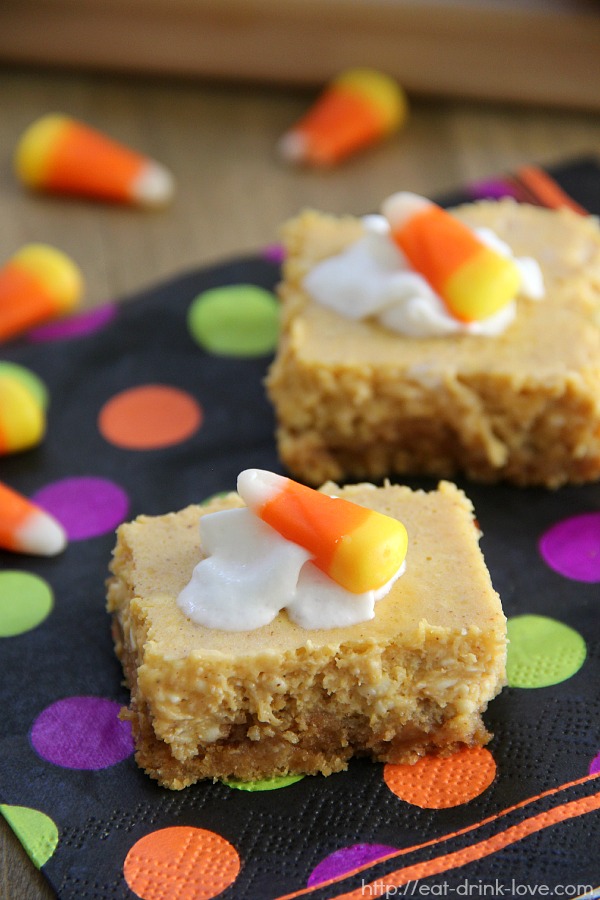 Pumpkin Cheesecake Bars on a polka dot napkin with whipped cream and candy corn