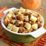 Apple Walnut Stuffing in a green ramekin with apples on top and an apple in the background on a striped napkin