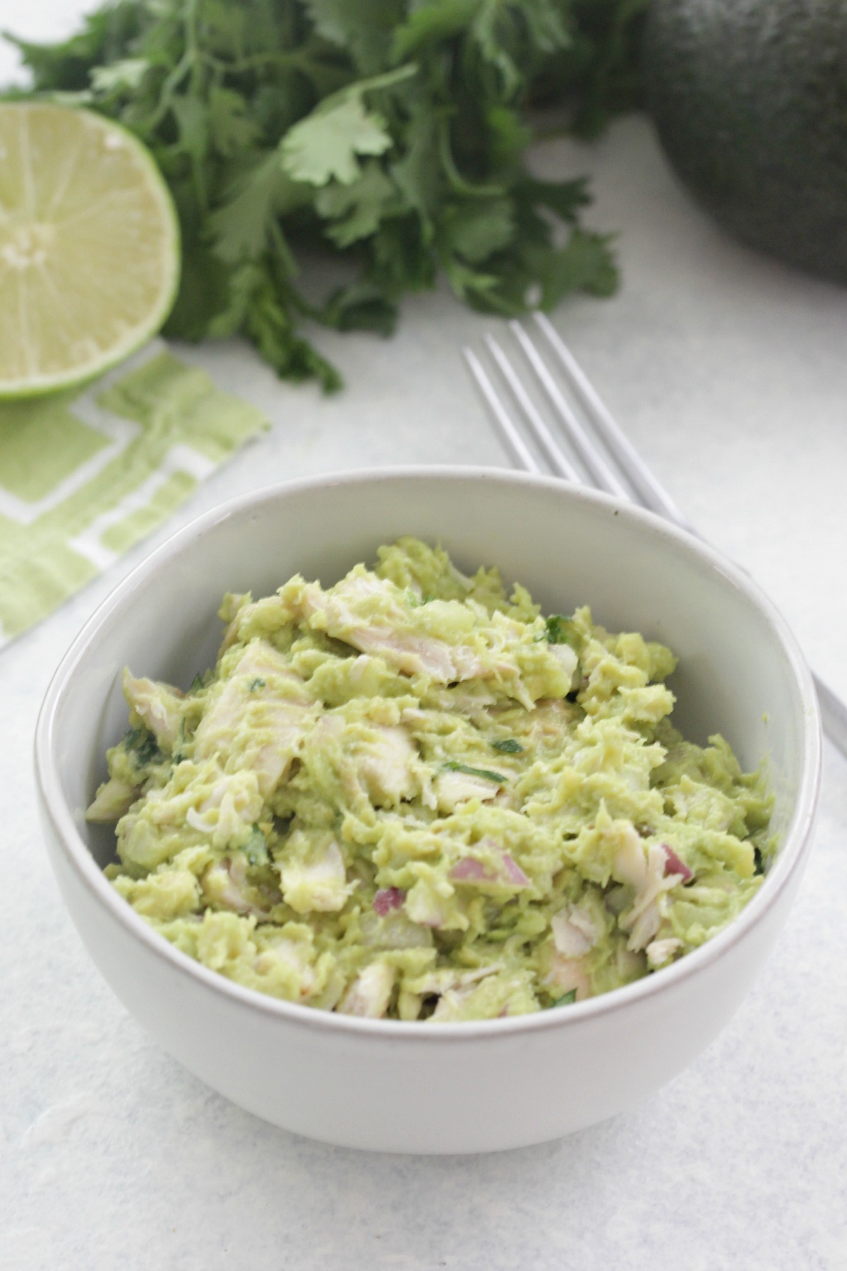 Avocado Chicken Salad in a white bowl with red onions, cilantro and lime