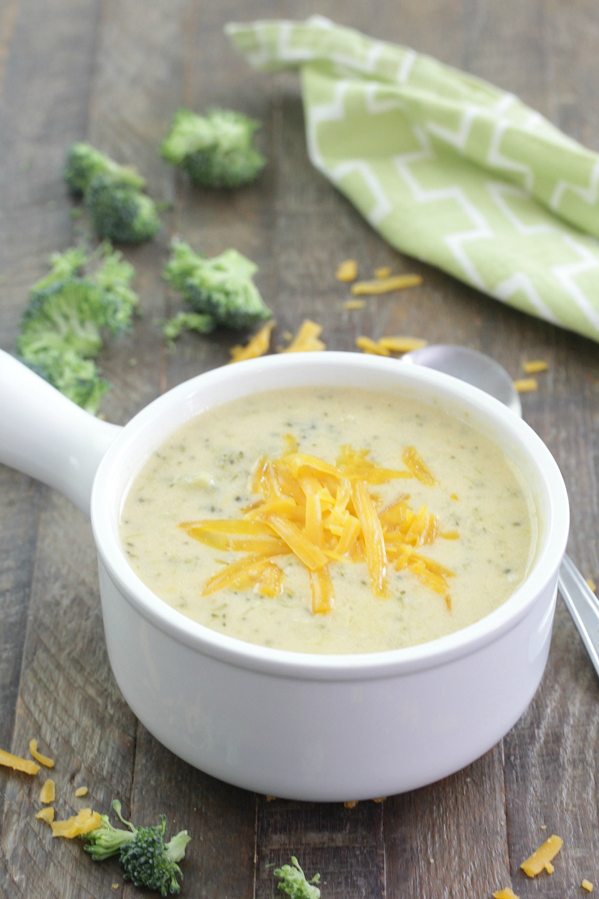 Instant Pot Broccoli Cheddar Soup in a white bowl with grated cheddar cheese on top