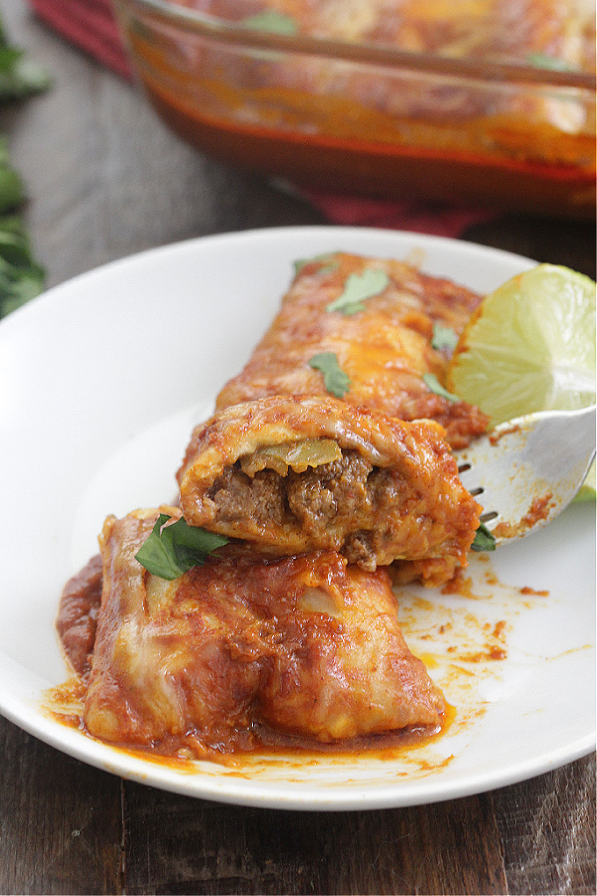 Spicy Beef Enchiladas on a white plate with a slice of lime
