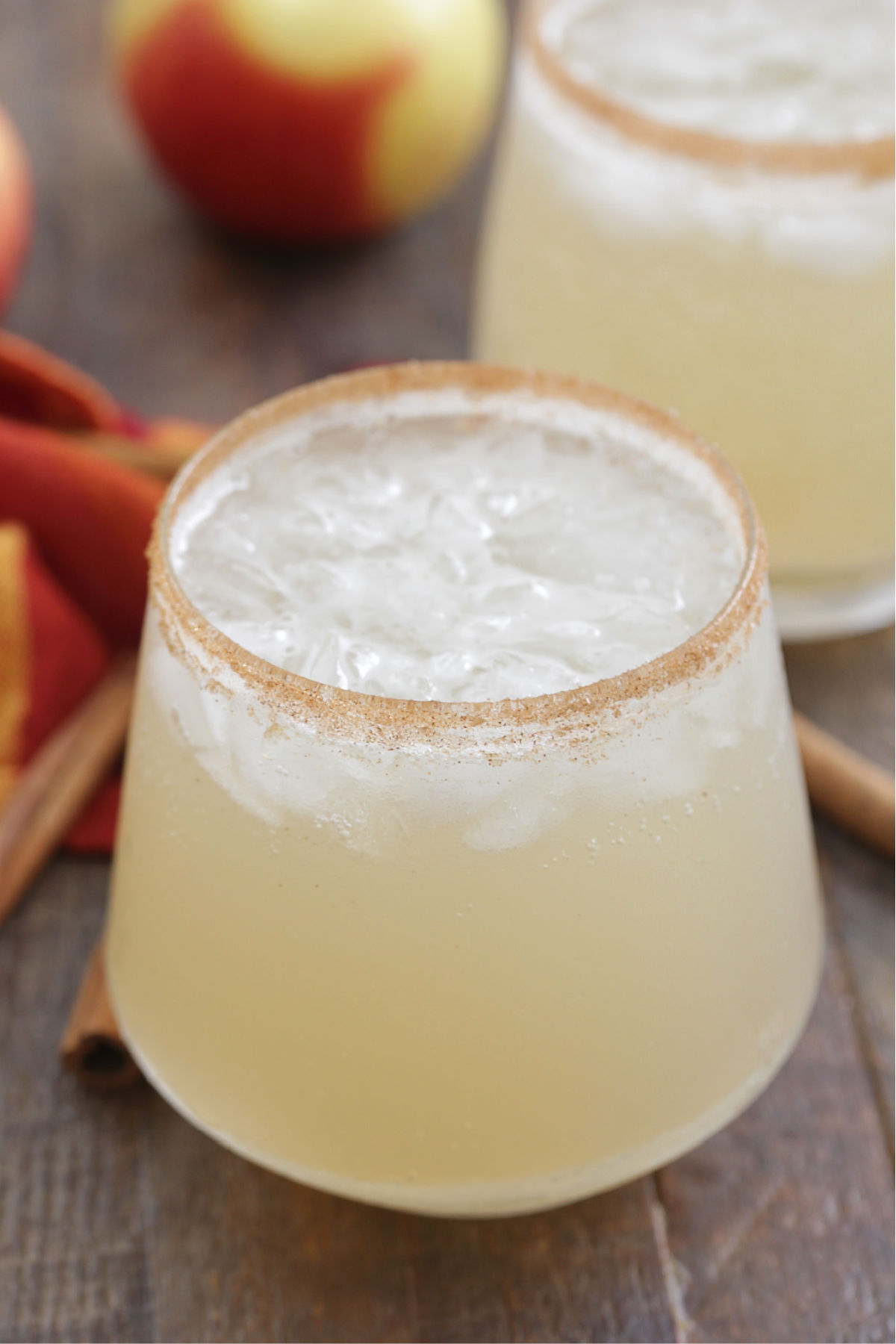 Close up of Apple Margaritas in a glass with a cinnamon sugar rim and apples