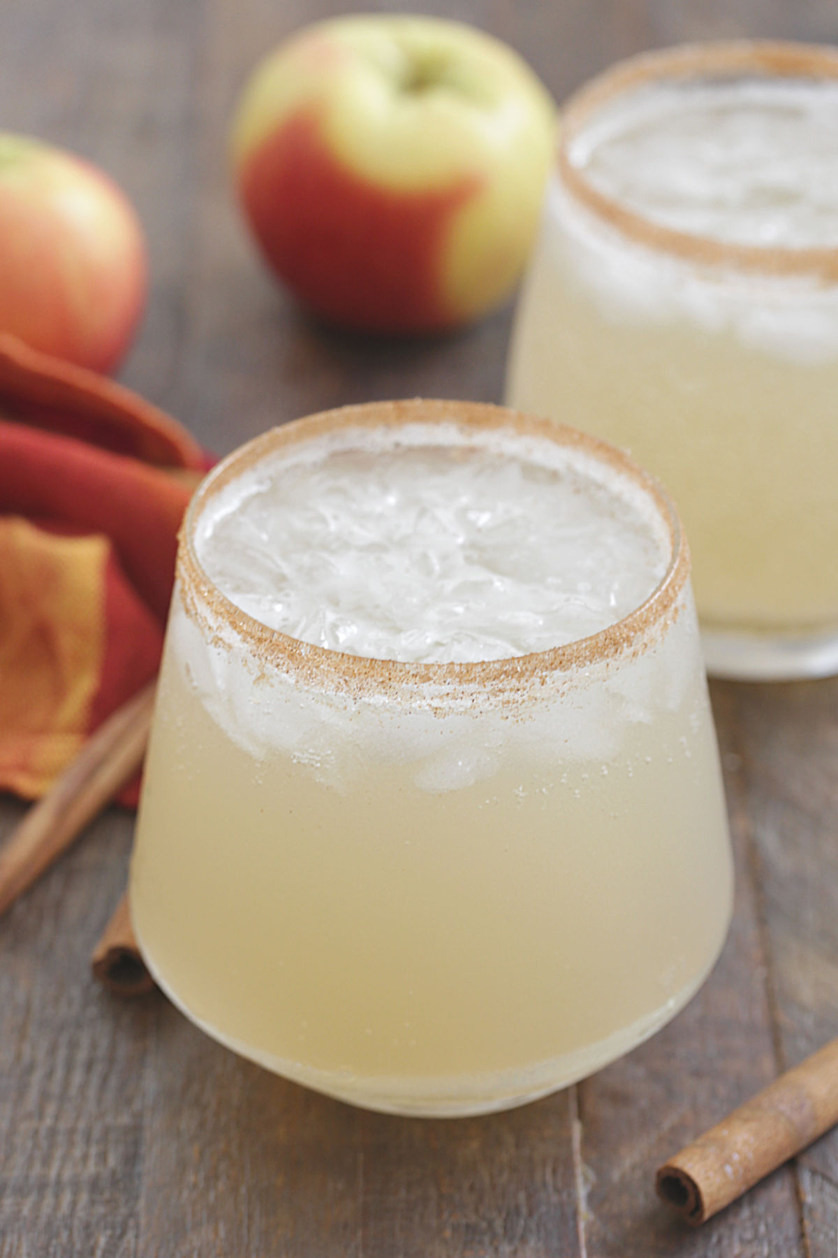 Apple Margaritas in a glass with a cinnamon sugar rim and apples