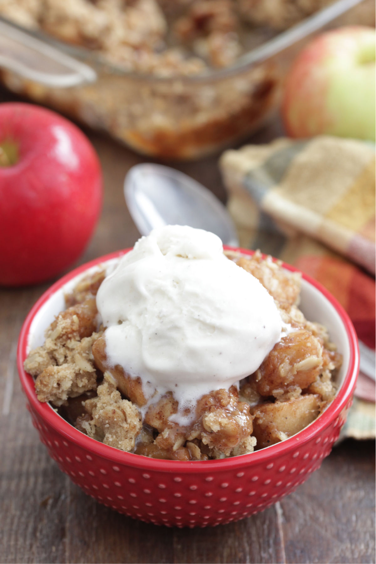 Caramel Apple Crisp in a red bowl with vanilla ice cream on top