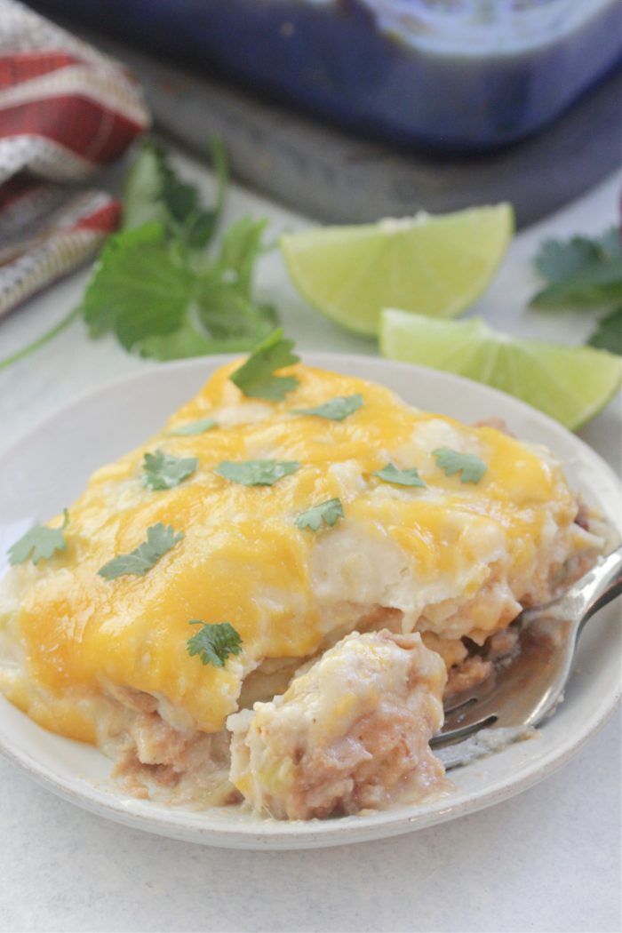 White Chicken Enchilada Casserole on a white plate with lime wedges