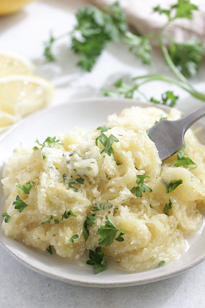 Lemon Ricotta Spaghetti on a white plate with parsley and lemon slices