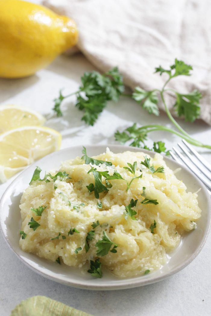 Lemon Ricotta Spaghetti on a white plate with parsley and lemon slices