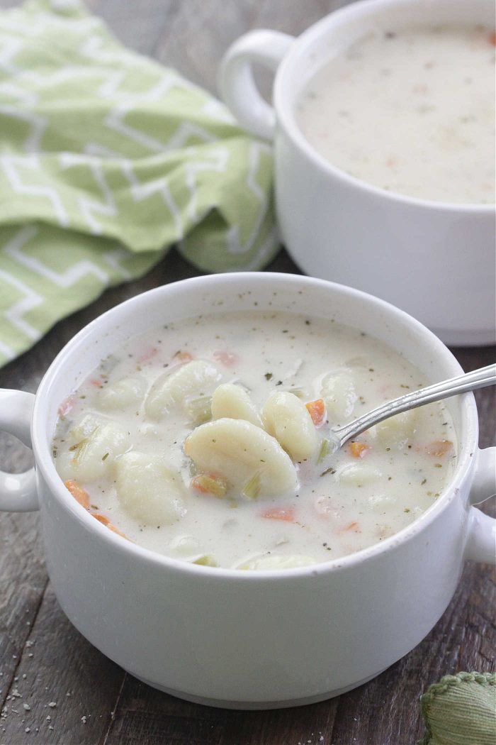 Close-up shot of creamy gnocchi soup in a white bowl