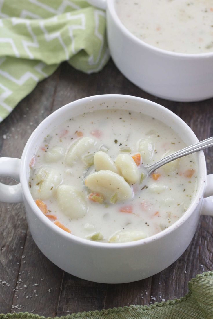 Creamy Gnocchi Soup in a white bowl with a spoon and green napkin