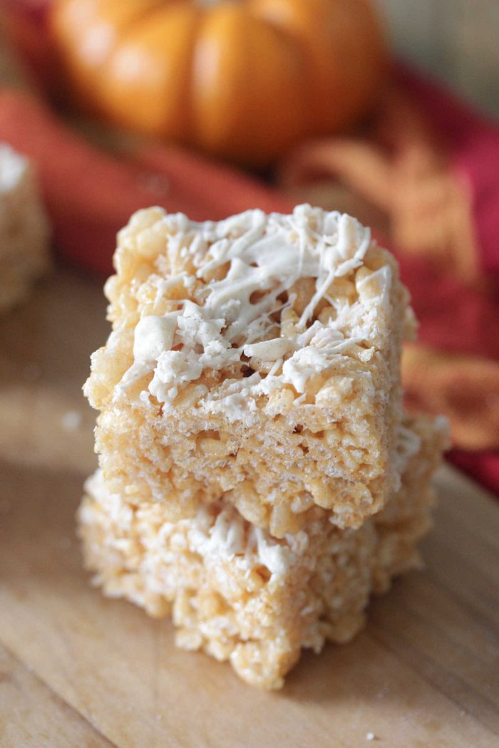 Pumpkin Rice Krispie Treats stacked on a board with red and orange napkin