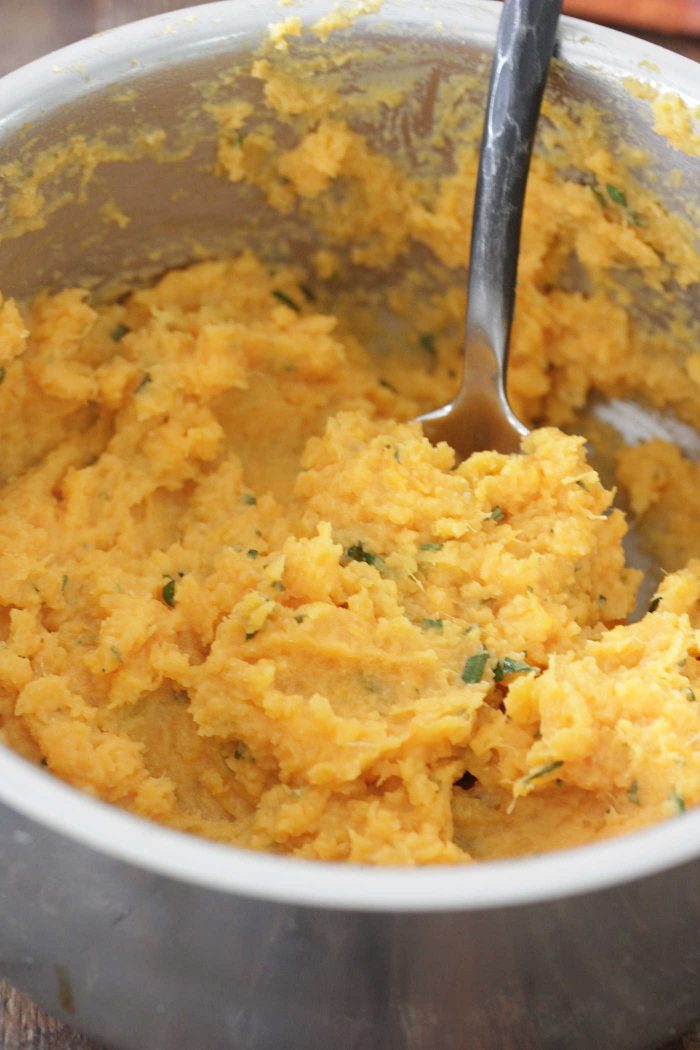 Herb and Brown Butter Mashed Sweet Potatoes in a pot with a spoon