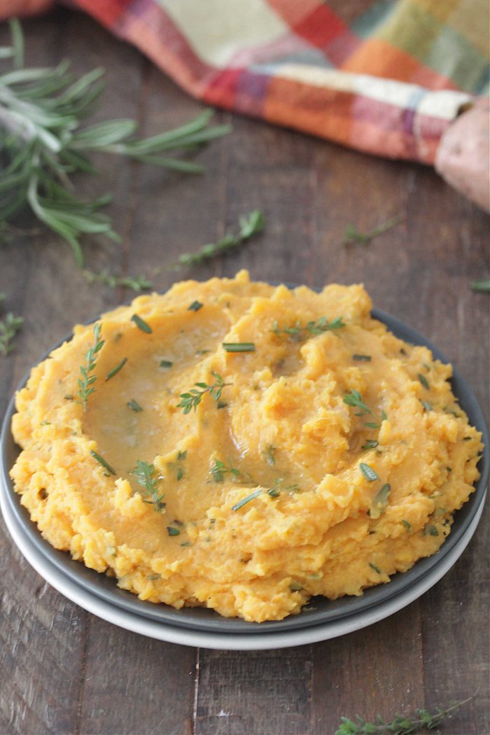 Herb and Brown Butter Mashed Sweet Potatoes on a blue plate with melted butter on top