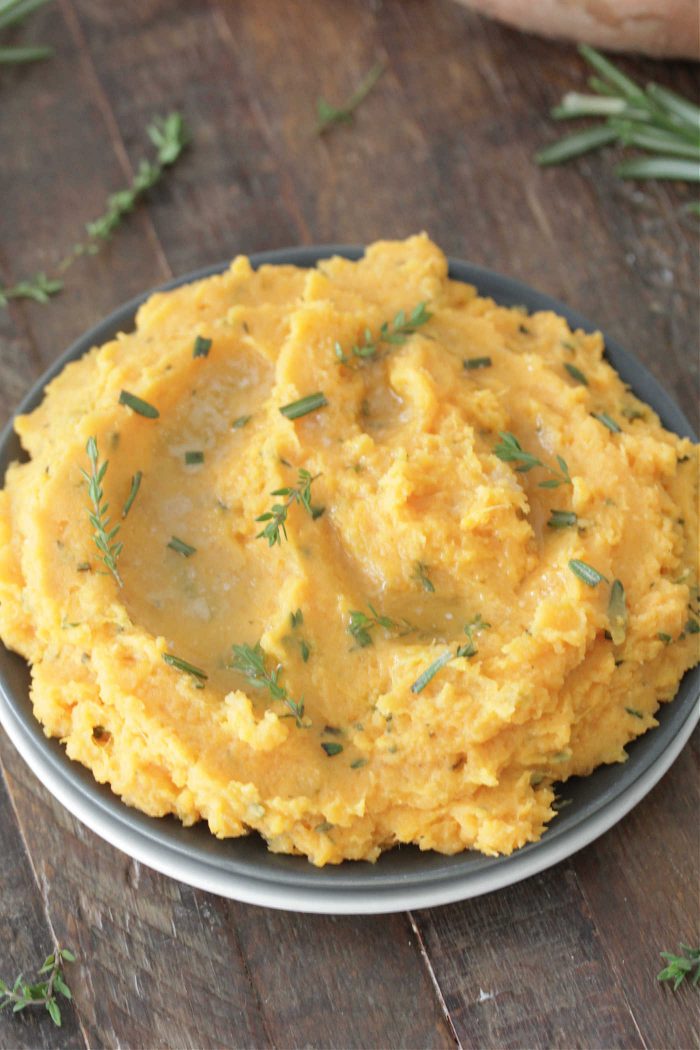 Herb and Brown Butter Mashed Sweet Potatoes on a blue plate with melted butter on top overhead shot