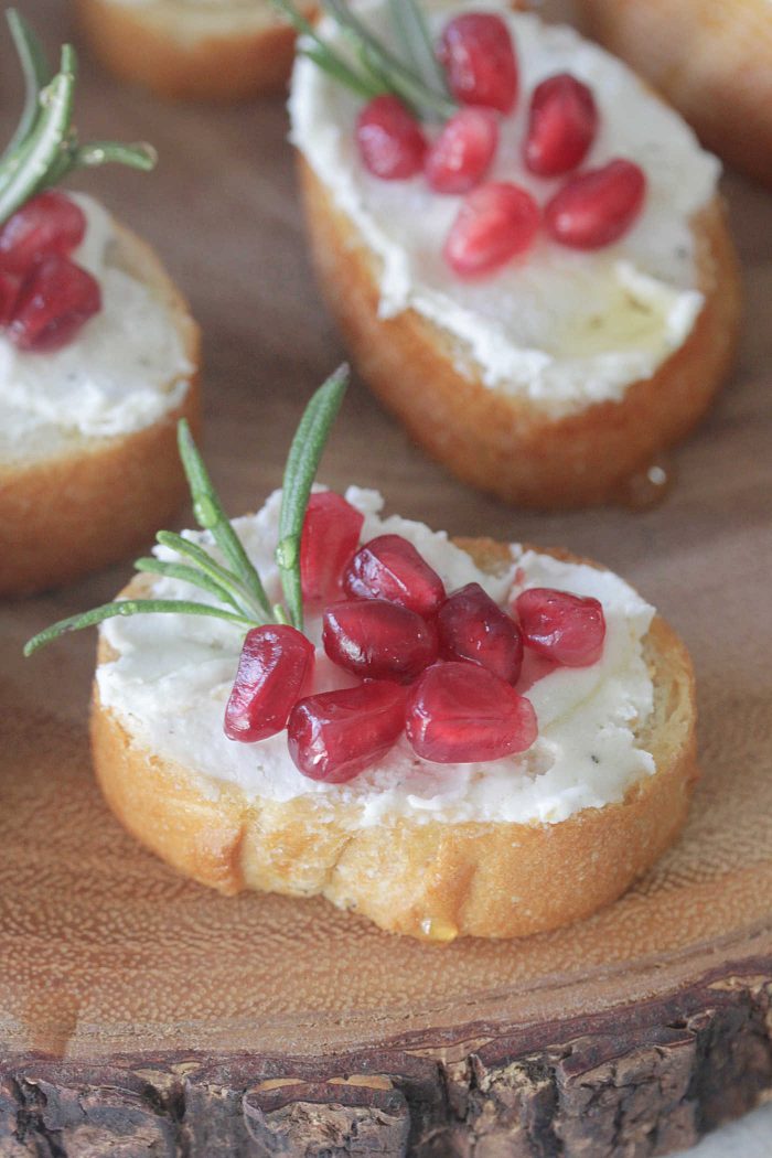 Herb Goat Cheese and Pomegranate Crostini with rosemary and honey drizzled on top