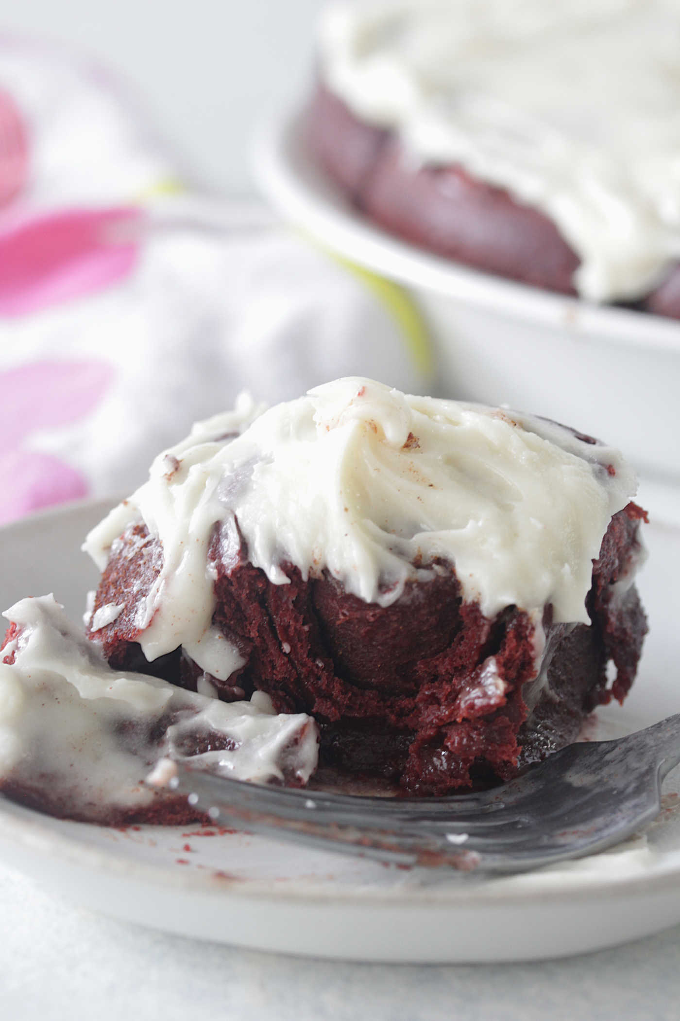 Red Velvet Cinnamon Roll on a plate broken with a fork