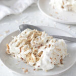 Coconut Ice Box Cake sliced on a white plate with shredded toasted coconut