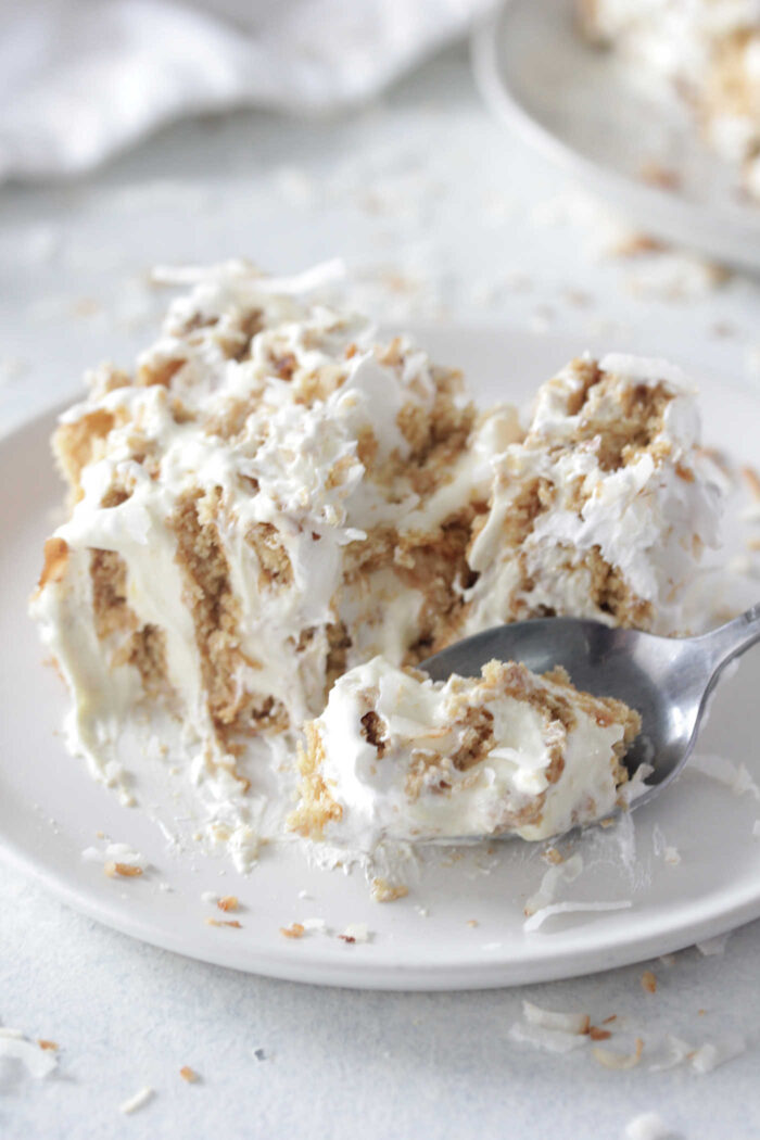 Coconut Ice Box Cake sliced with a spoon scooping some cake