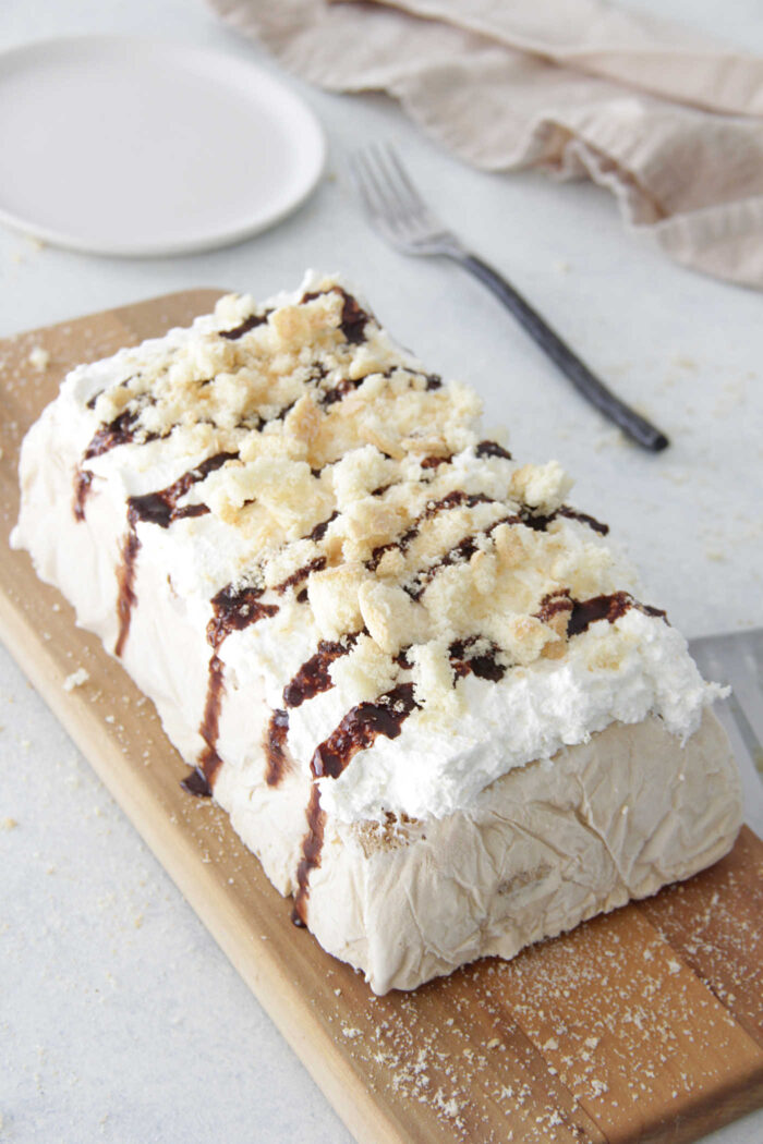 Tiramisu Ice Cream Cake on a wooden serving board with lady finger crumbs on top