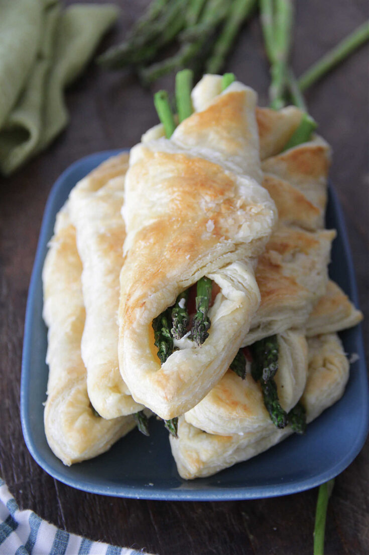 Asparagus & Bacon Wrapped Puff Pastries stacked on a blue plate