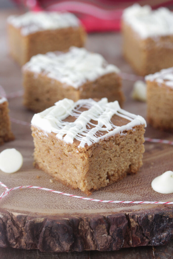 Gingerbread Blondies sliced into squares on a wooden board with white chocolate chips