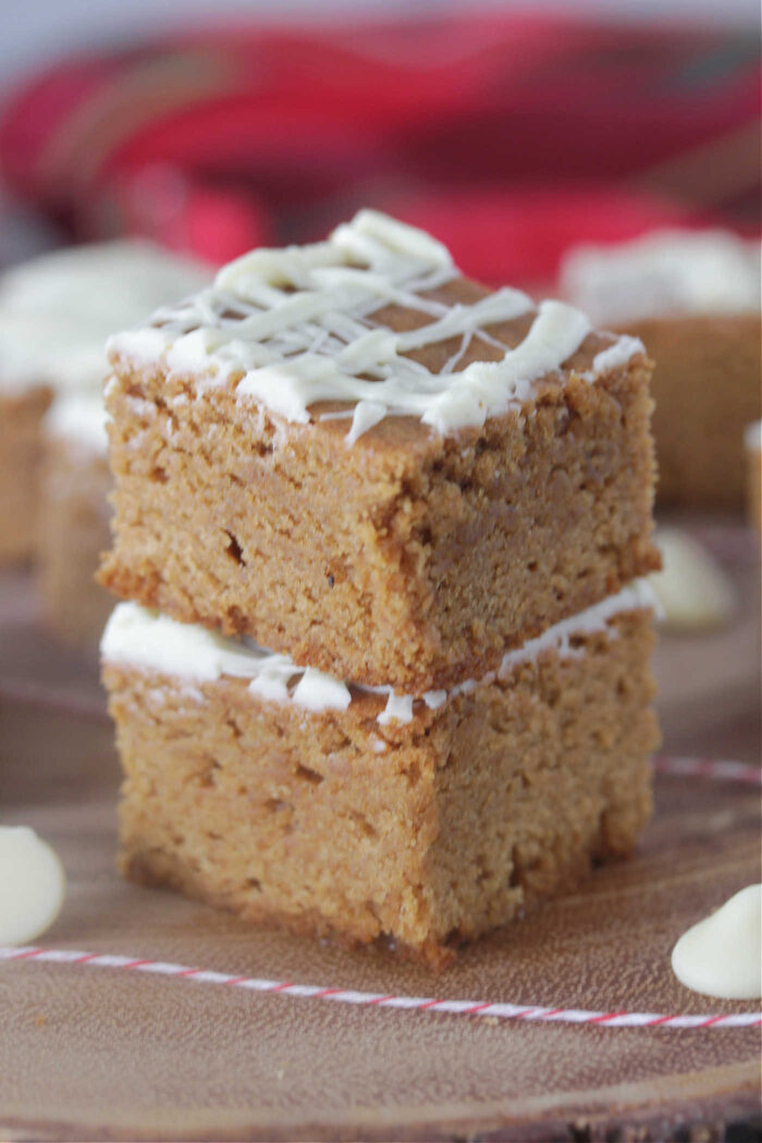 Two gingerbread blondies stacked on a wooden board with twine and white chocolate chips