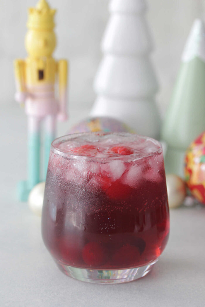 Close up photo of Sugar Plum Fairy Punch with white wooden christmas tree in background