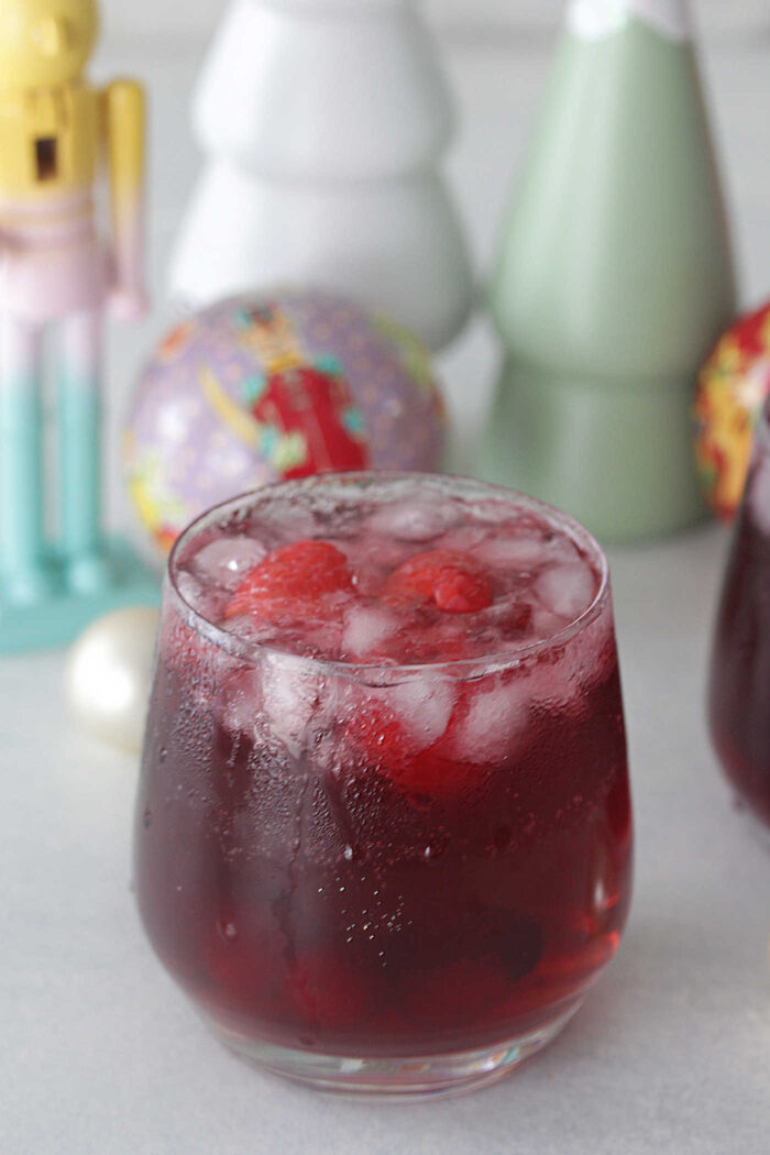 Sugar Plum Fairy Punch in a glass with a nutcracker and ornaments behind it