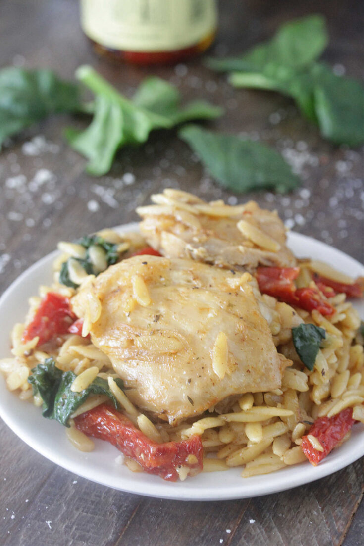 One-Pot Tuscan Chicken & Orzo on a plate with spinach and sun dried tomatoes