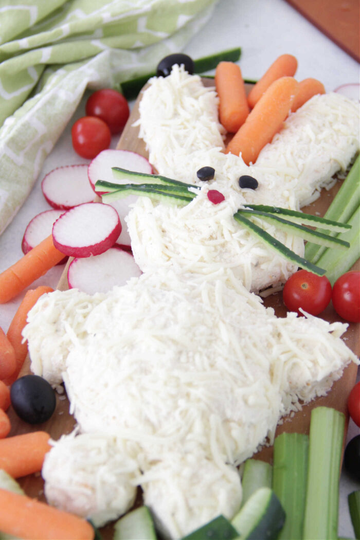 Easter Bunny Cheese Ball on a wooden serving board with carrots, tomatoes, and celery