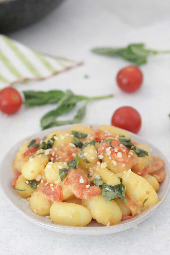 Gnocchi with Creamy Tomato Basil Sauce on a white plate with fresh basil on top