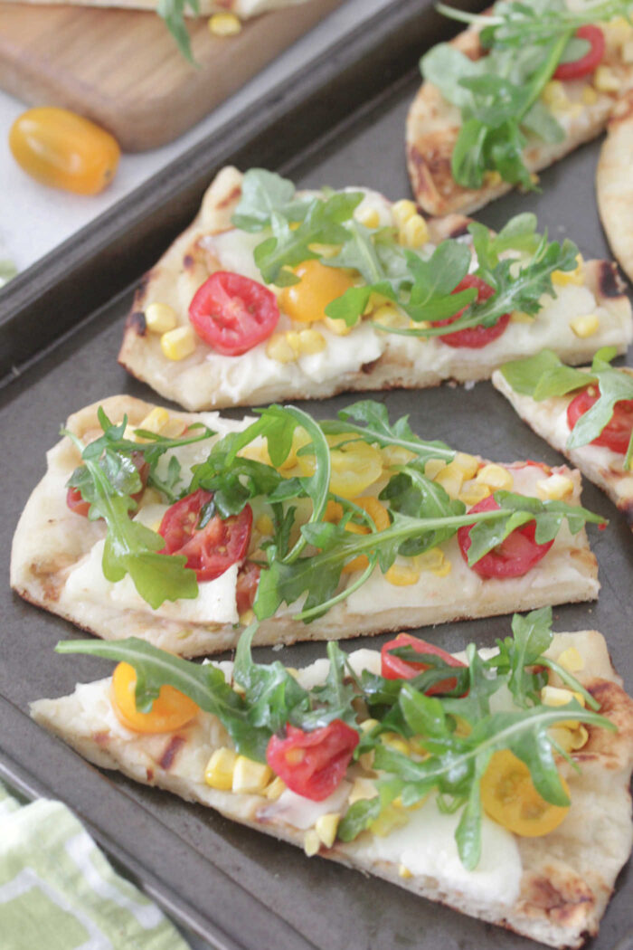 Slices of grilled flatbread pizzas on a baking sheet