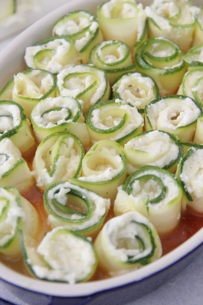 Zucchini Lasagna Roll Ups unbaked in a blue baking dish