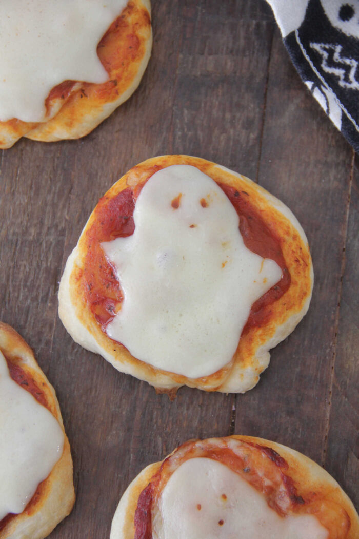 Overhead picture of mini ghost pizzas arranged on a dark wooden board