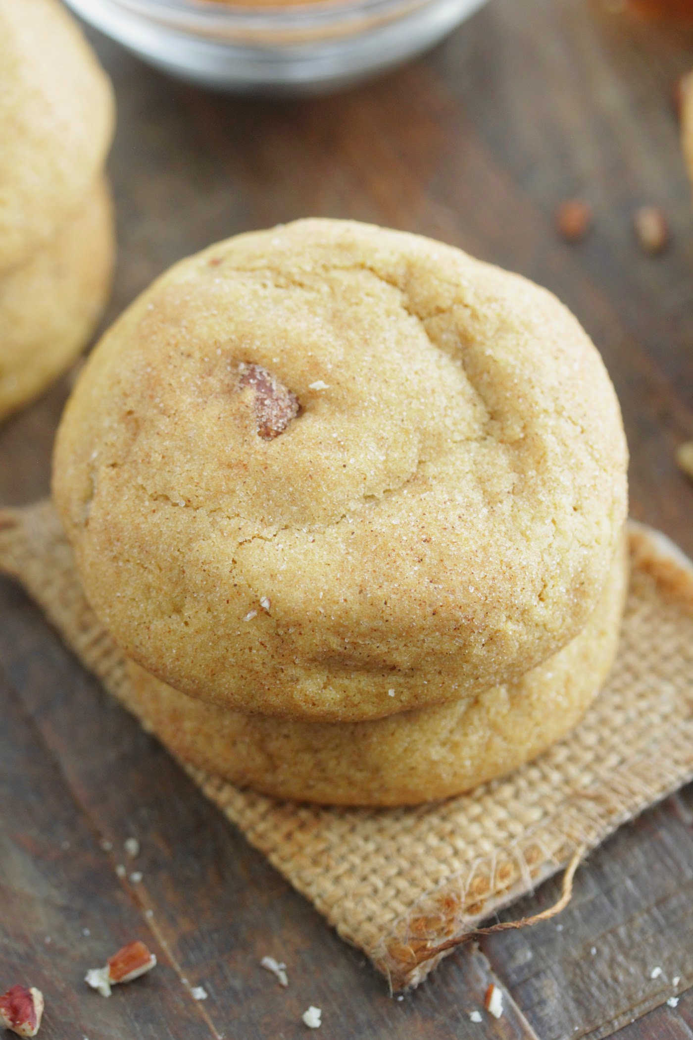 Brown Butter Pumpkin Cookies stacked on a piece of cloth with chopped pecans