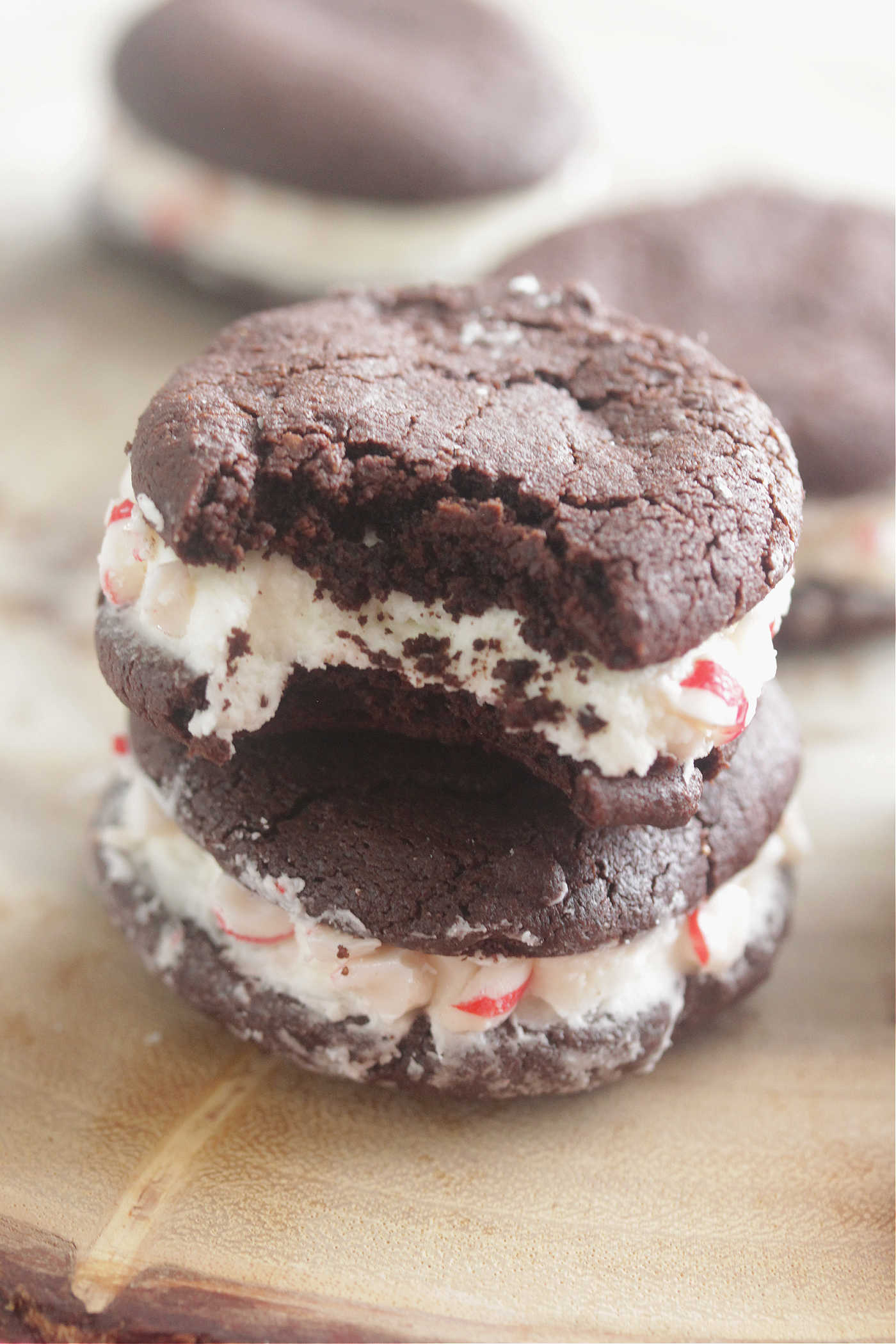 Chocolate Peppermint Sandwich Cookies stacked on top of each other on a dark wooden board
