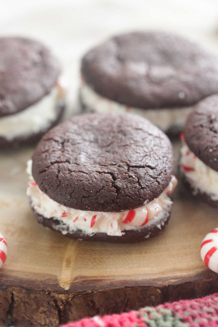 Chocolate Peppermint Sandwich Cookies on a wooden board with crushed peppermint candies